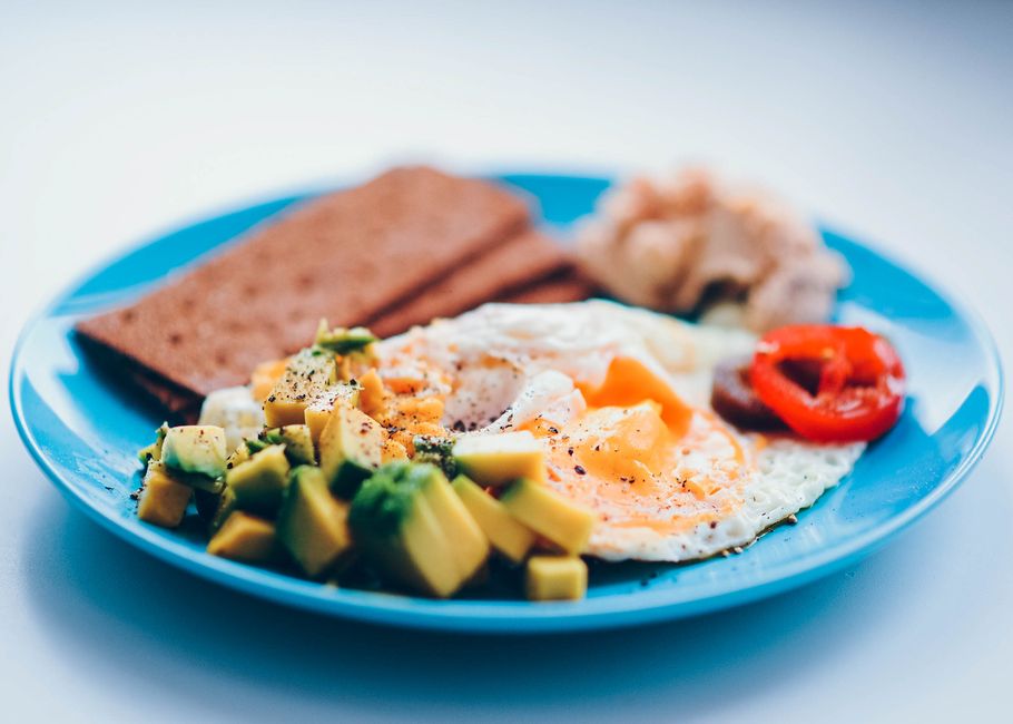 Assorted high calorie foods for bulking including nuts, avocado, eggs, and whole grains arranged on a wooden table