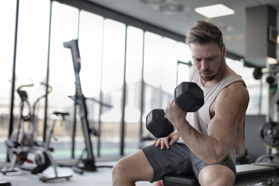 A frustrated lifter examining muscles in mirror, getting stronger but not gaining muscle size despite consistent training