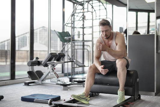 Person holding sore muscles after exercise, illustrating when to worry about workout soreness versus normal post-workout pain
