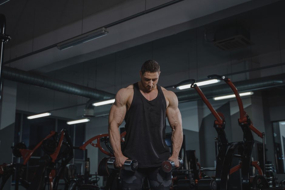 Flexing man in gym showing muscle gains progress timeline illustrating how long does it take to see muscle gains