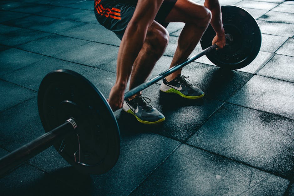 Athlete adding weight plates to barbell in gym demonstrating how to apply progressive overload for strength gains